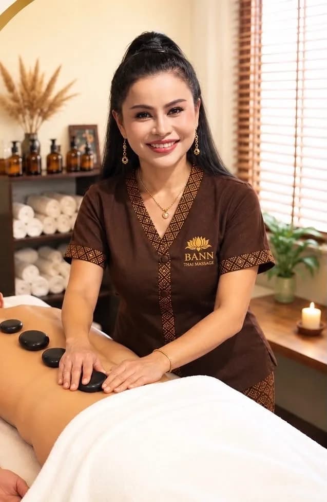 Therapist of BANN Thaimassage giving a hot stone massage A therapist of BANN Thaimassage in Basel placing warm basalt stones on a guest's back during a hot stone massage